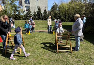 w ogródku przedszkolnym odbywają się sportowe konkurencje, w których uczestniczą dzieci