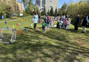 w ogródku przedszkolnym odbywają się sportowe konkurencje, w których uczestniczą dzieci