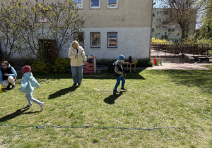 w ogródku przedszkolnym odbywają się sportowe konkurencje, w których uczestniczą dzieci