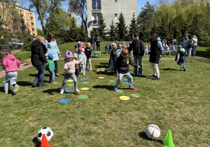 w ogródku przedszkolnym odbywają się sportowe konkurencje, w których uczestniczą dzieci
