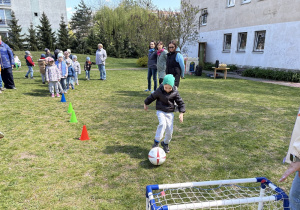 w ogródku przedszkolnym odbywają się sportowe konkurencje, w których uczestniczą dzieci