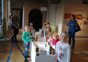 Dzieci z grupy 1 pozują do zdjęcia przy makiecie Łódzkich budynków.