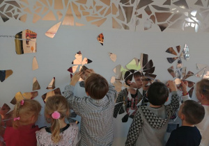 Dzieci z grupy 1 układają mozaikę na ścianie.