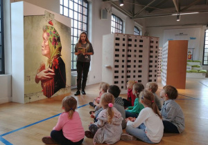 Dzieci z grupy 1 słuchają pracownika muzeum, który opowiada im o muralach.