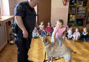 Dziecko głaszcze psa policyjnego.