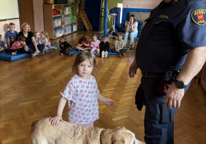 Dziecko głaszcze psa policyjnego.