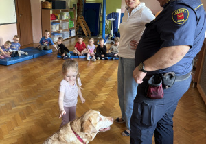 Dziecko głaszcze psa policyjnego.