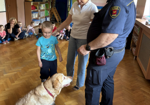 Dziecko głaszcze psa policyjnego.
