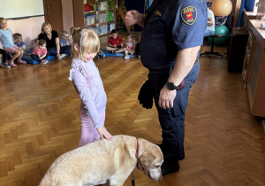 Dziecko głaszcze psa policyjnego.