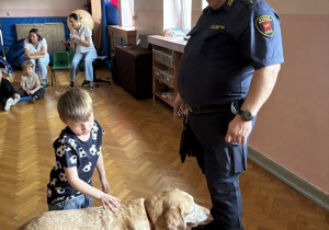 Dziecko głaszcze psa policyjnego.