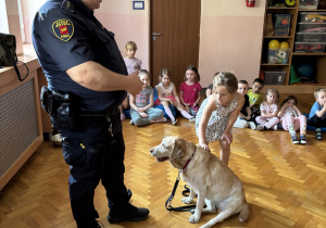 Dziecko głaszcze psa policyjnego.