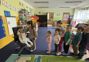 Dzieci ustawione w rzędzie podchodzą do dziewczynki.