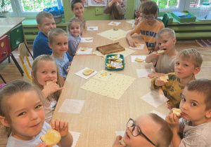 Dzieci siedzą przy stole i kosztują miodu.