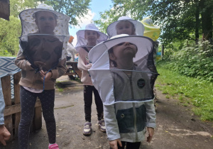 dzieci podczas wycieczki do pasieki w Lipce ubrane są w stroje pszczelarza