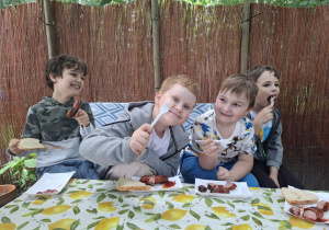 dzieci podczas wycieczki do pasieki w Lipce jedzą kiełbaski