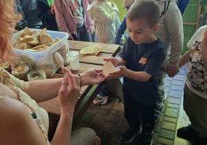 dzieci podczas wycieczki do pasieki w Lipce jedzą chleb z miodem