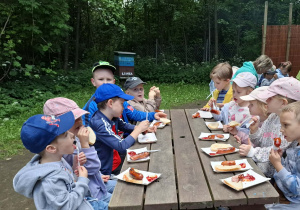 dzieci podczas wycieczki do pasieki w Lipce jedzą kiełbaski