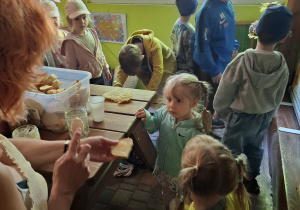 dzieci podczas wycieczki do pasieki w Lipce jedzą chleb z miodem