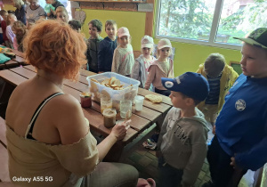 dzieci podczas wycieczki do pasieki w Lipce jedzą chleb z miodem