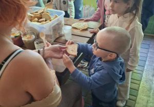 dzieci podczas wycieczki do pasieki w Lipce jedzą chleb z miodem