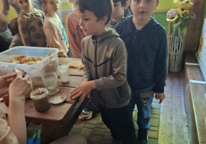 dzieci podczas wycieczki do pasieki w Lipce jedzą chleb z miodem