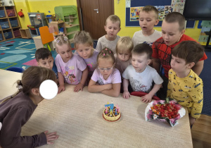 dziewczynka obchodzi urodziny, na stoliku widać tort z cyferką 7