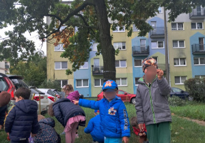 Dzieci na spacerze zbierają skarby jesieni.