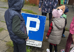 Dzieci stoją przy znaku drogowym.