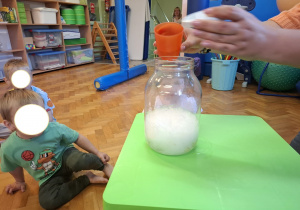 dzieci biorą udział w zajęciach sensorycznych, dotykają, chodzą, obserwują materiały przyrodnicze
