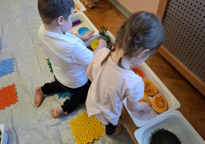 dzieci biorą udział w zajęciach sensorycznych, dotykają, chodzą, obserwują materiały przyrodnicze