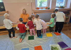 dzieci biorą udział w zajęciach sensorycznych, dotykają, chodzą, obserwują materiały przyrodnicze