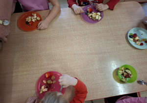 dzieci samodzielnie wykonują sałatkę z różnych owoców
