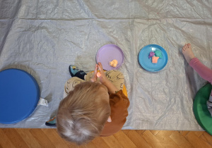 zajęcia sensoryczne na sali gimnastycznej, dzieci malują, dotykają stopami i dłońmi różnych faktur