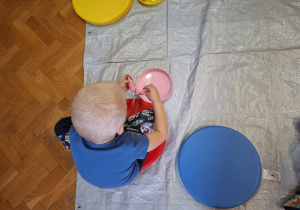 zajęcia sensoryczne na sali gimnastycznej, dzieci malują, dotykają stopami i dłońmi różnych faktur