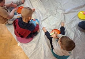 zajęcia sensoryczne na sali gimnastycznej, dzieci malują, dotykają stopami i dłońmi różnych faktur