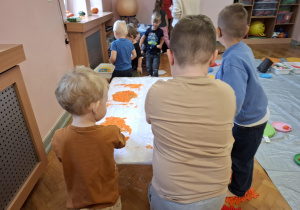zajęcia sensoryczne na sali gimnastycznej, dzieci malują, dotykają stopami i dłońmi różnych faktur