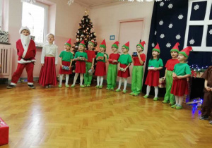Święty Mikołaj wraz z żoną i elfami z grupy IV śpiewają piosenkę.