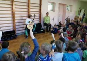 Dzieci odgadują zagadki muzyczna grane przez Huberta na gitarze.