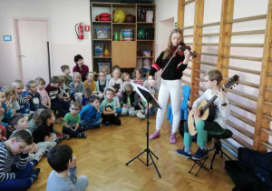 Hubert i Justyna grają na instrumentach, a dzieci słuchają.