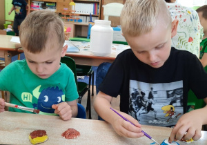 Dzieci malują muszelki wykonane z masy solnej.