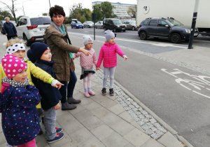 Nauczyciel pokazuje dzieciom ścieżkę rowerową.