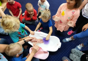 Dzieci uczą się samodzielnie kąpać lalkę.