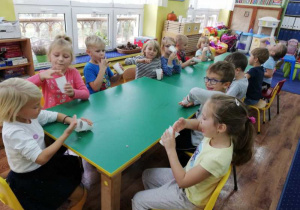 Dzieci siedzą przy stole i piją koktajl.