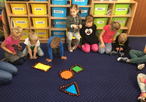 Dzieci układają z kasztanów figury geometryczne.