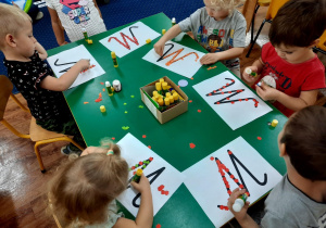 Młodsze dzieci wyklejają kontur poznanej litery jesiennymi symbolami.