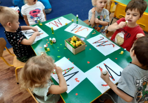 Młodsze dzieci wyklejają kontur poznanej litery jesiennymi symbolami.