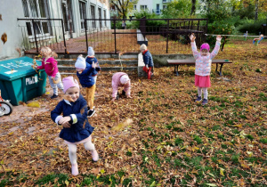Dzieci bawią się liśćmi w ogrodzie przedszkolnym.