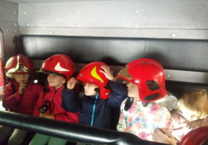 Czworo dzieci w wozie bojowym w hełmach.