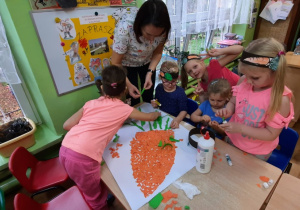 Dzieci wykonują wydzierankę z kolorowego papieru.