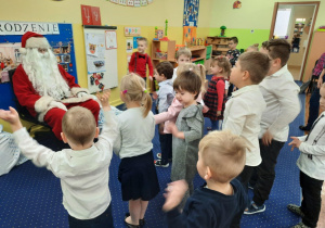 Dzieci śpiewają Mikołajowi kolędę.
